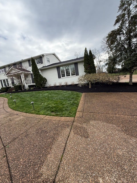 After spring cleanup in Brentwood TN with pruned perennials, trimmed shrubs, freshly mowed lawn, and premium black mulch installed