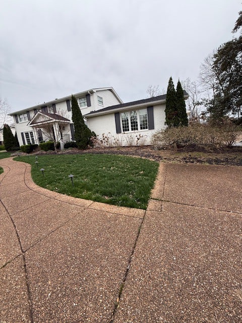 Before spring cleanup in Brentwood TN showing overgrown perennials, untrimmed shrubs, and no mulch installed