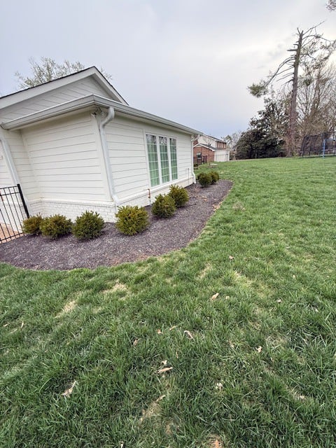 Before spring cleanup in Brentwood TN showing overgrown perennials, untrimmed shrubs, and no mulch installed